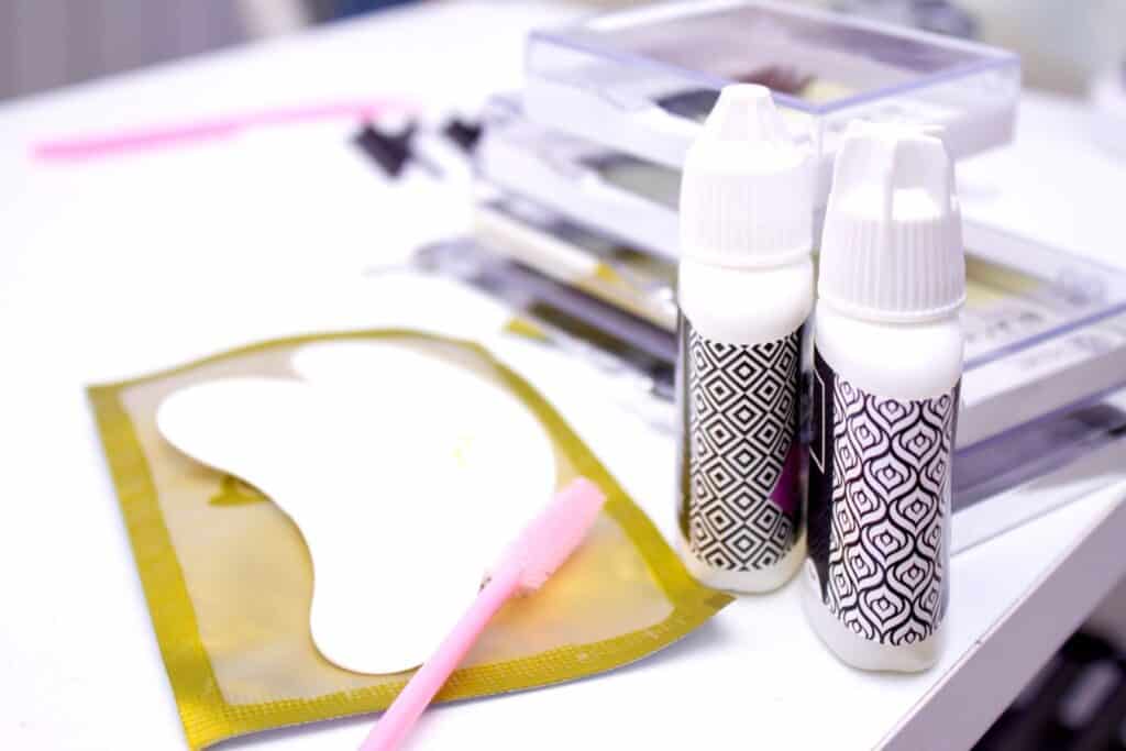 eyelash glue and eyelash tools on a white table inside a salon