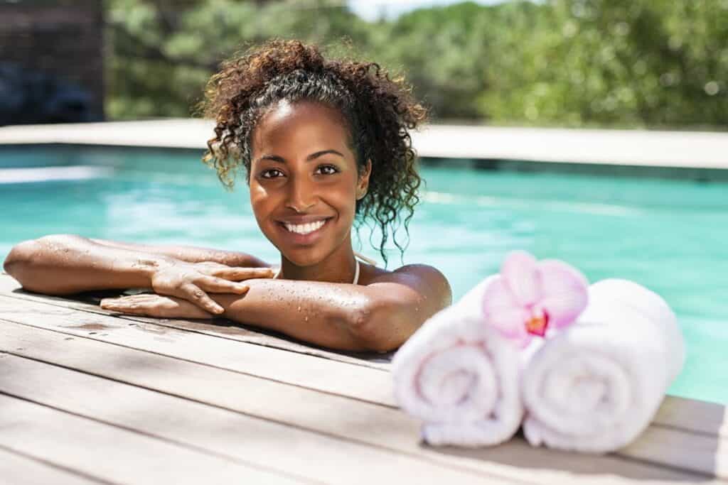 woman smiling resting on the side of a swimming pool