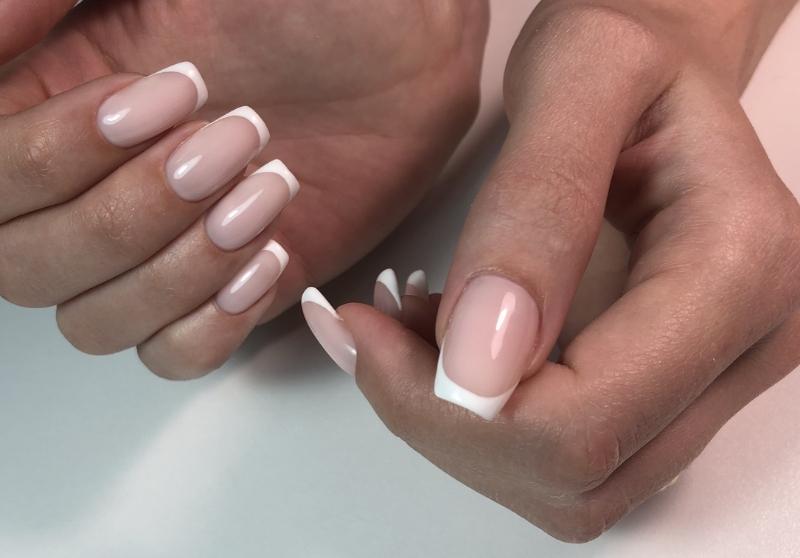 Close up image of a woman's hands with a beige colored manicure.