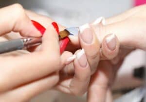 close up of nails being painted blue by another pair of hands.