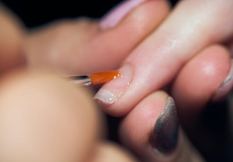 Close up of a nail being painted with clear nail varnish. 