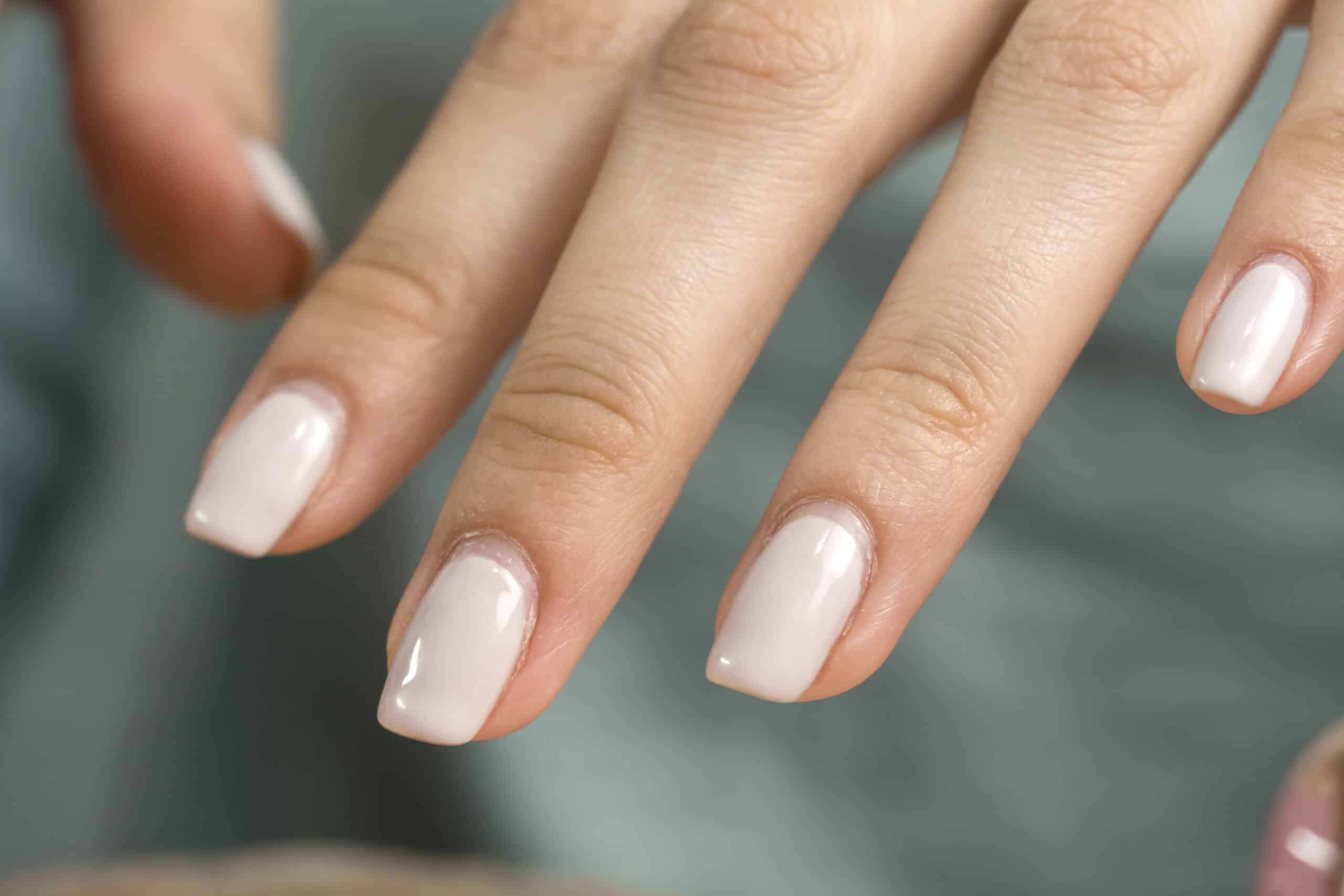 close up of woman's hands with light colored nail polish.