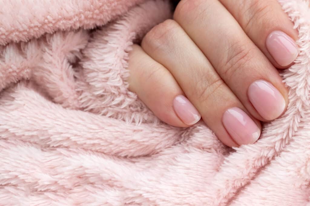 close up of hand with manicured nails and a pink fluffy fleece.