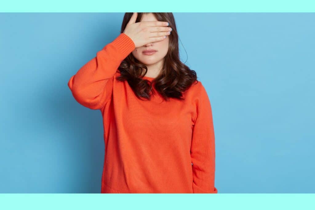woman covering her eye in front of blue background