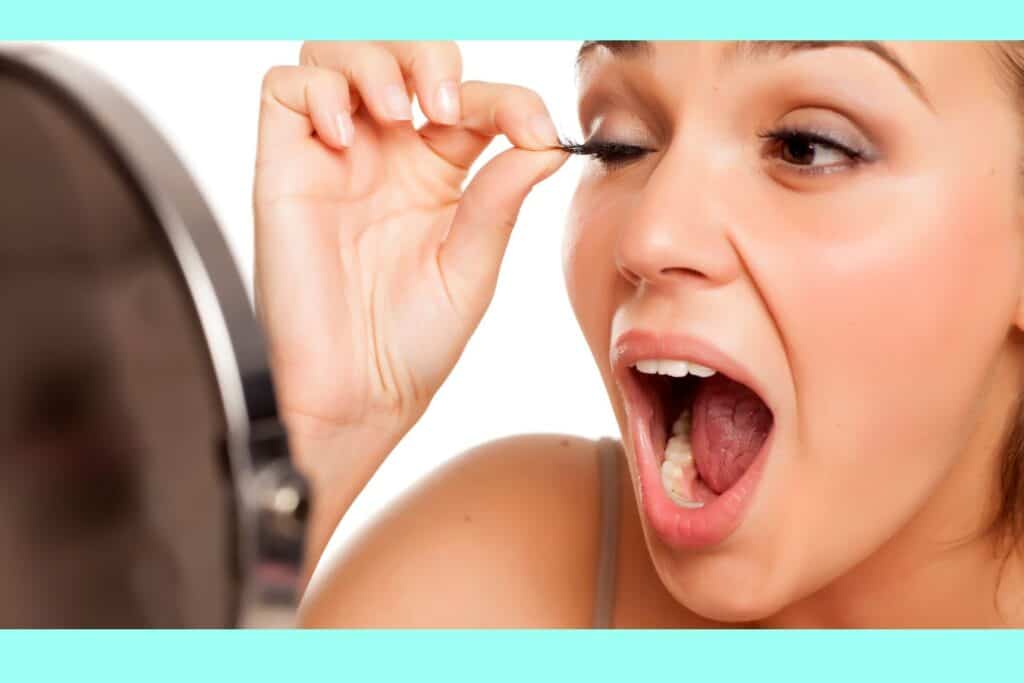 woman looking in the mirror pulling on her eyelash