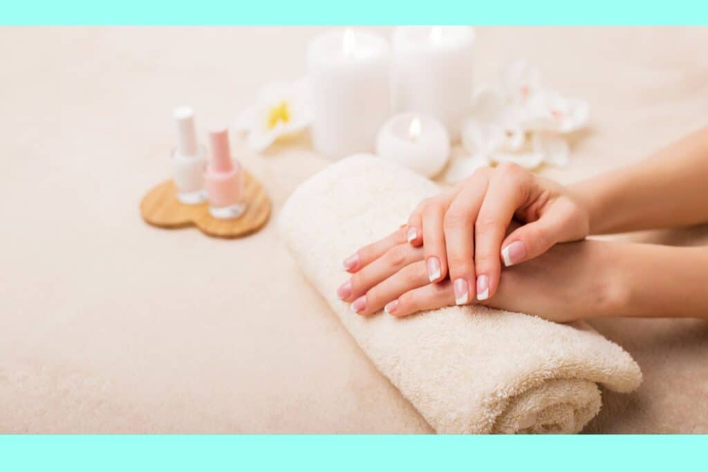 a woman resting her hands on a towel next to nail polish